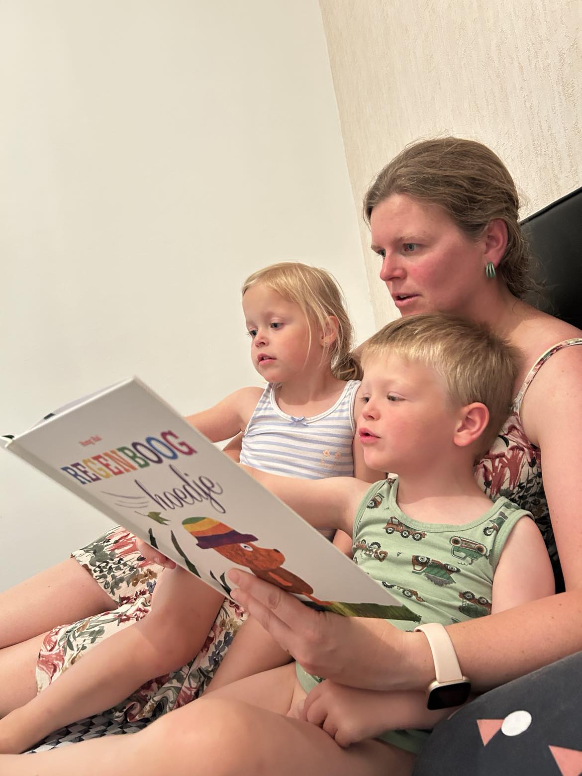 Moeder en kinderen ontdekken het verhaal van Regenboog hoedje op een knus moment voor het slapengaan.